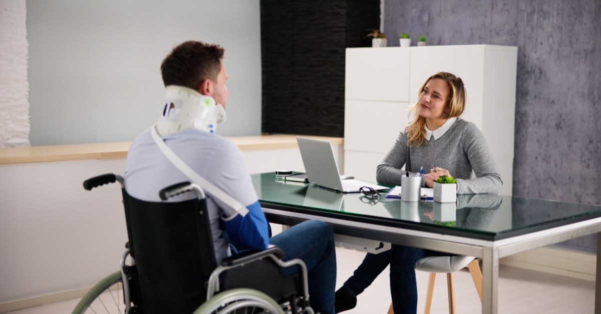 Paciente con lesión de columna en silla de ruedas reunido con su abogada para revisar su caso legal